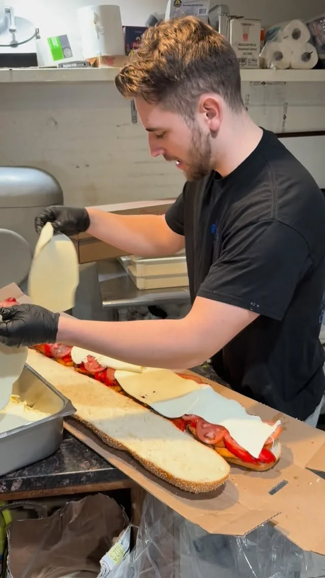 Anthony preparing a hero with fresh mozzarella and roasted peppers
